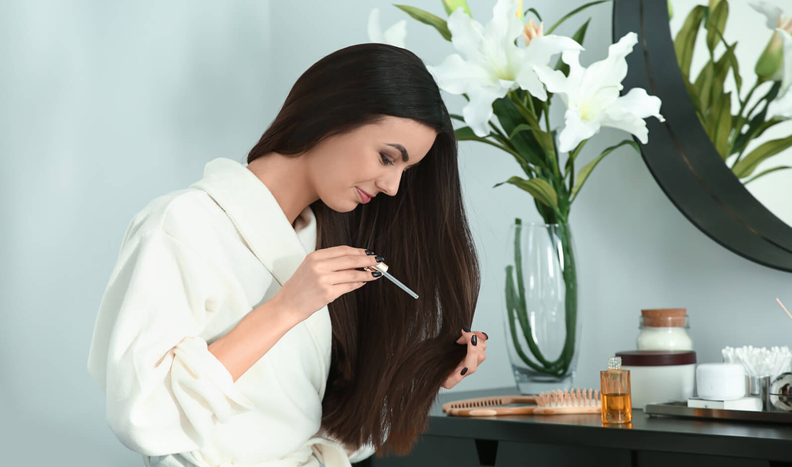 Ragazza che si applica un olio vegetale con oli essenziali sui capelli